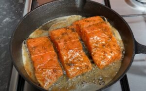 Salmon fillets, seasoned and glistening, sizzle in a hot pan